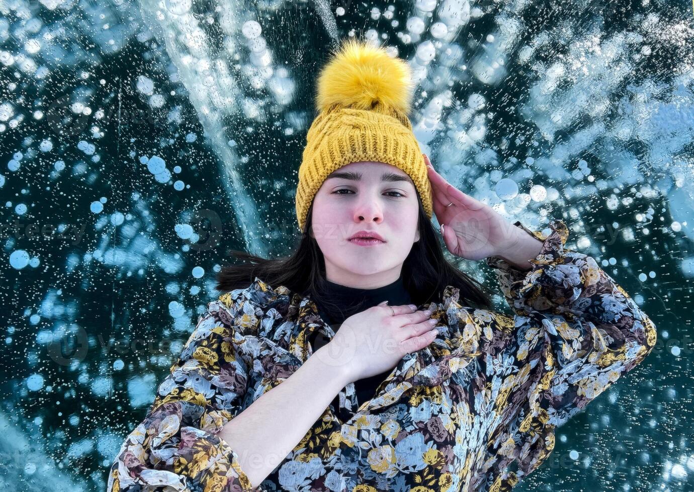 Fashionable image of a stunning woman posing on Baikal Lake ice wearing yellow hat photo