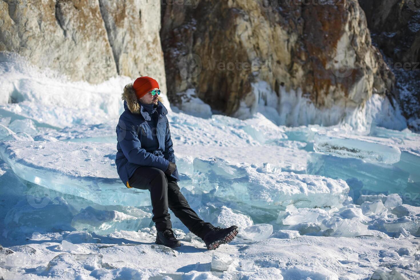 Portrait of the man tourist in red cap and blue jacket wearing sunglasses on ice photo