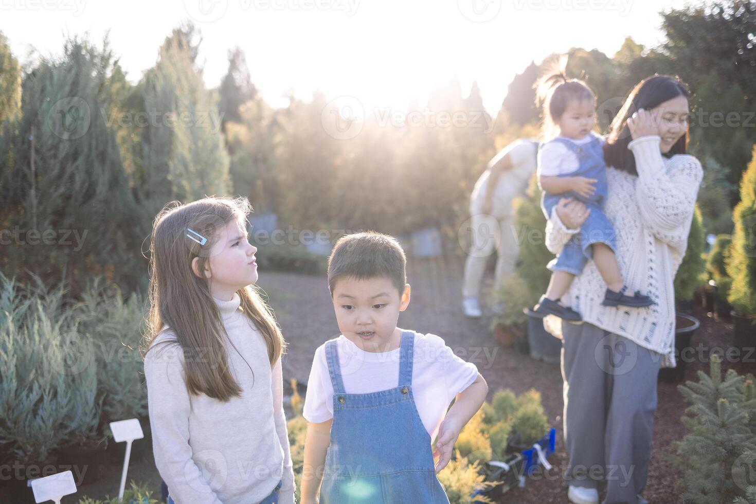 Asian parents and cute kids in a plant nursery. A young married couple with children choose planters for their garden. photo