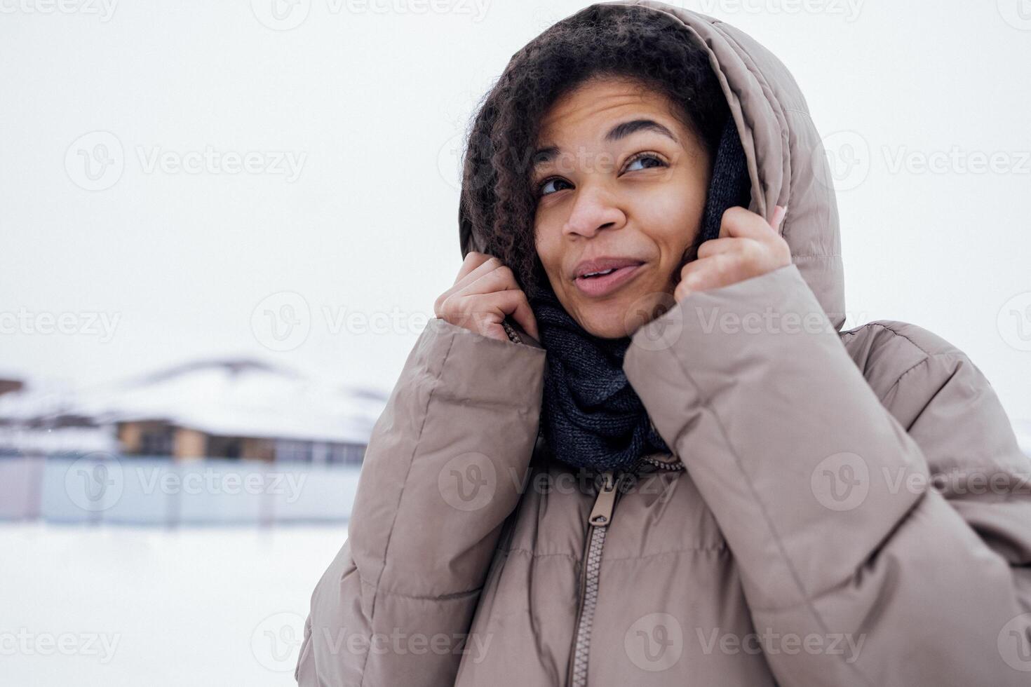 Close up of beautiful mixed race girl feels cold and wraps herself up in knitted woolen scarf photo