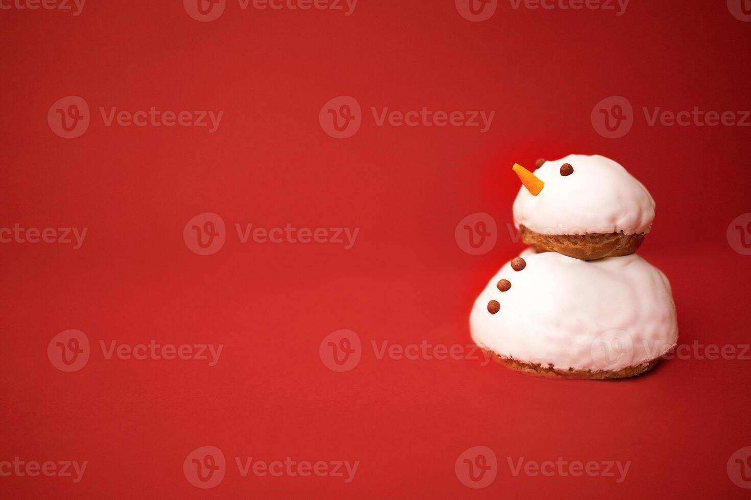 A little cute snowman made of cookies and white cream with chocolate buttons and eyes. Bright red background. Minimalism. Christmas holiday celebrate concept. Happy New Year eve atmosphere. photo