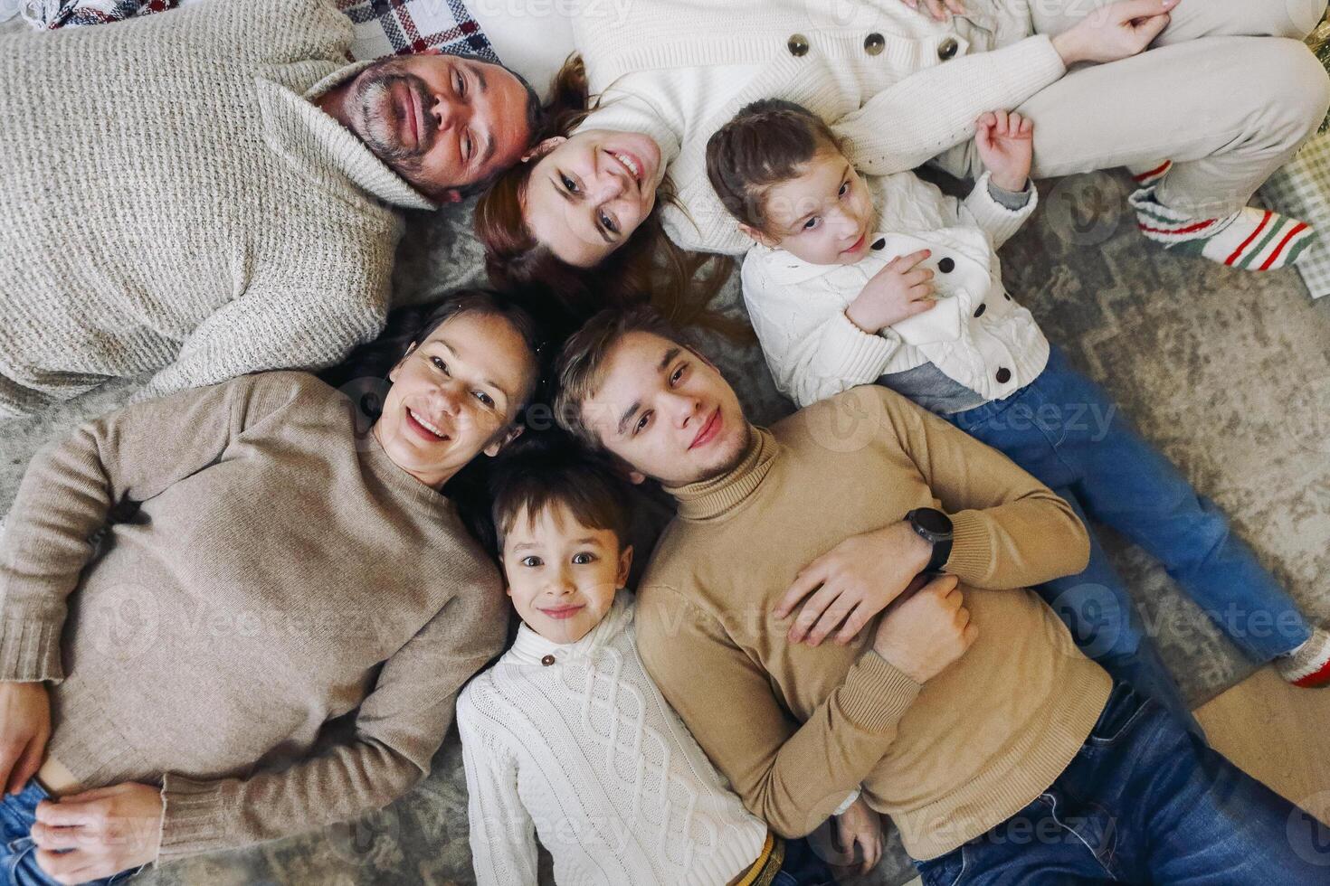Top view of happy big multi-generation family lying in circle on floor and smiling at camera photo