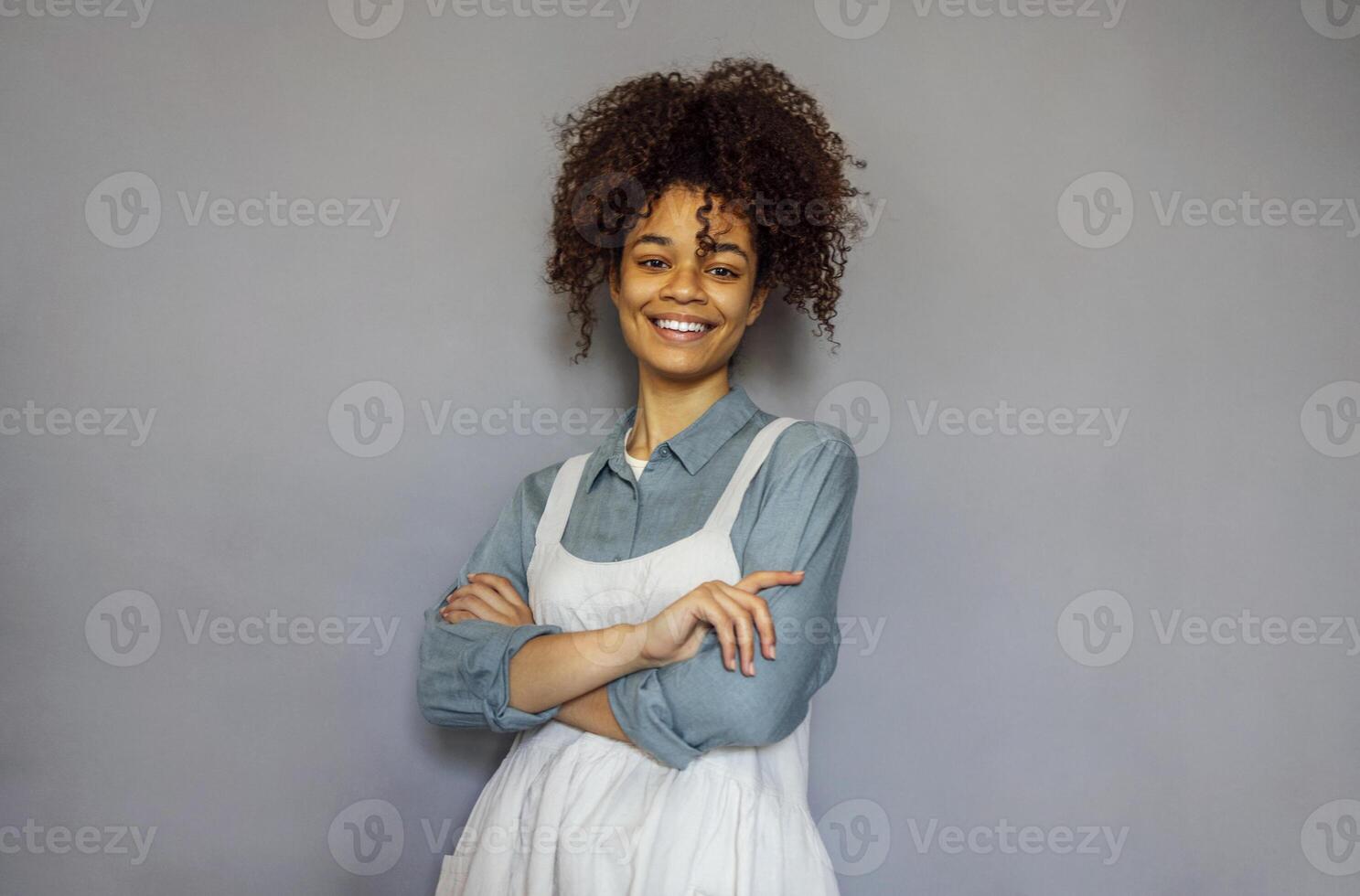 Young black woman wearing beige apron isolated on grey background with copy space. photo