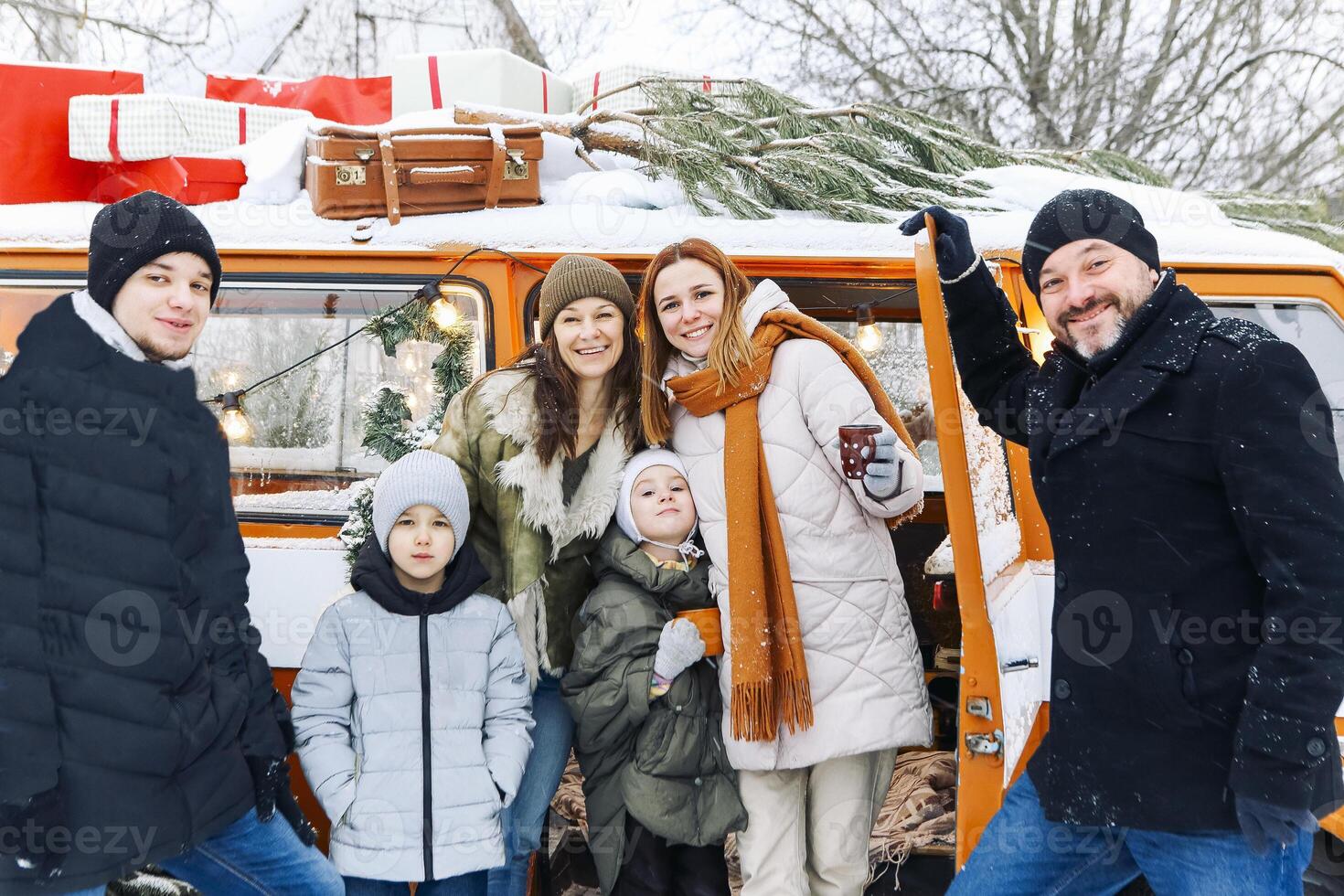 Happy family of travelers in minivan lying together at open rear doors and smiling at camera photo