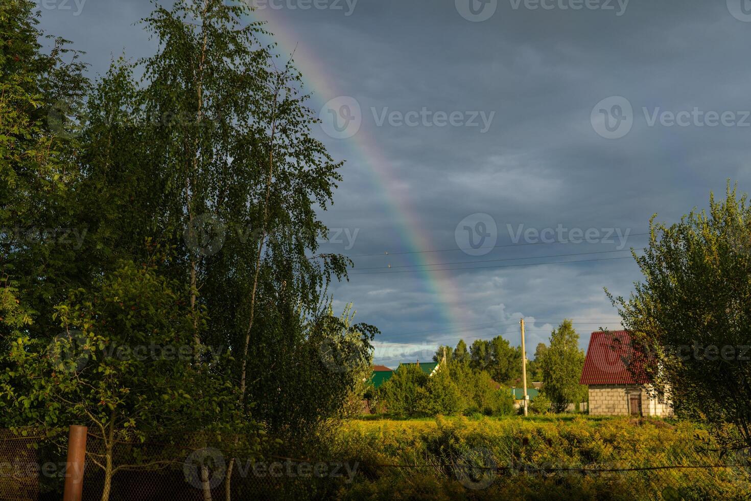A rainbow in the village after the rain. Clouds in the sky photo