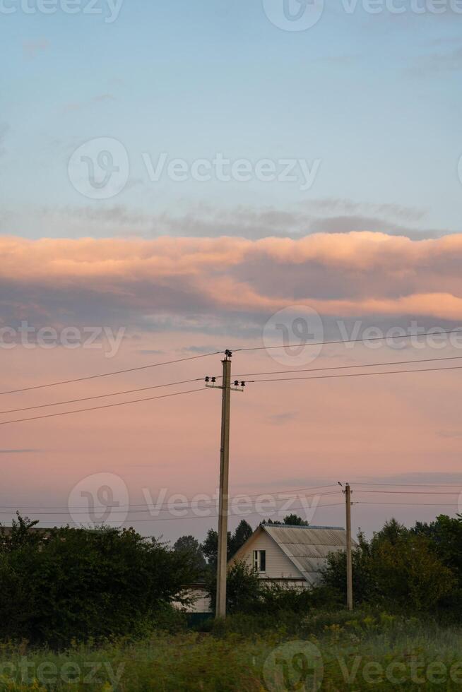 The support of power lines against the background of an orange sunset sky photo