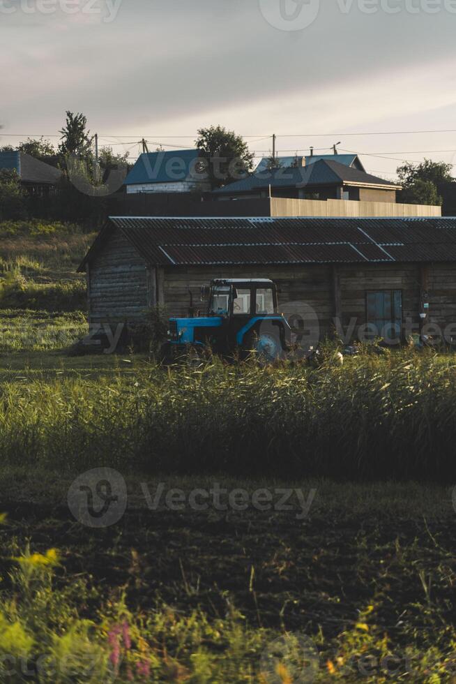 Blue tractor in the evening, at sunset after a hard day's work.A green field photo