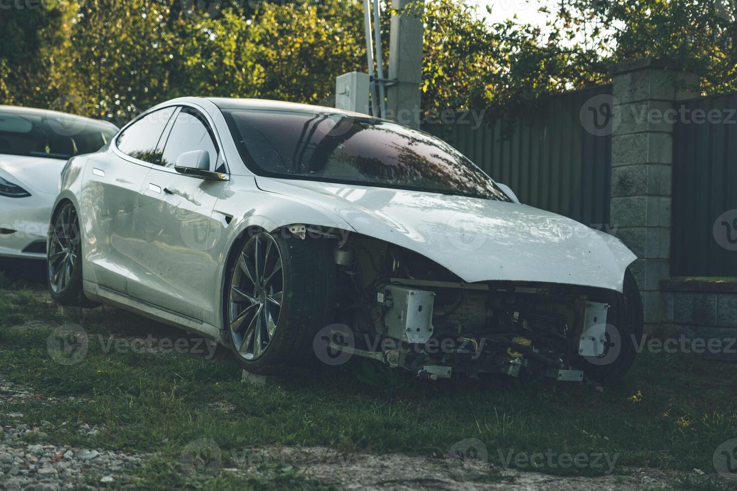 A broken Tesla model s without headlights stands in the village photo