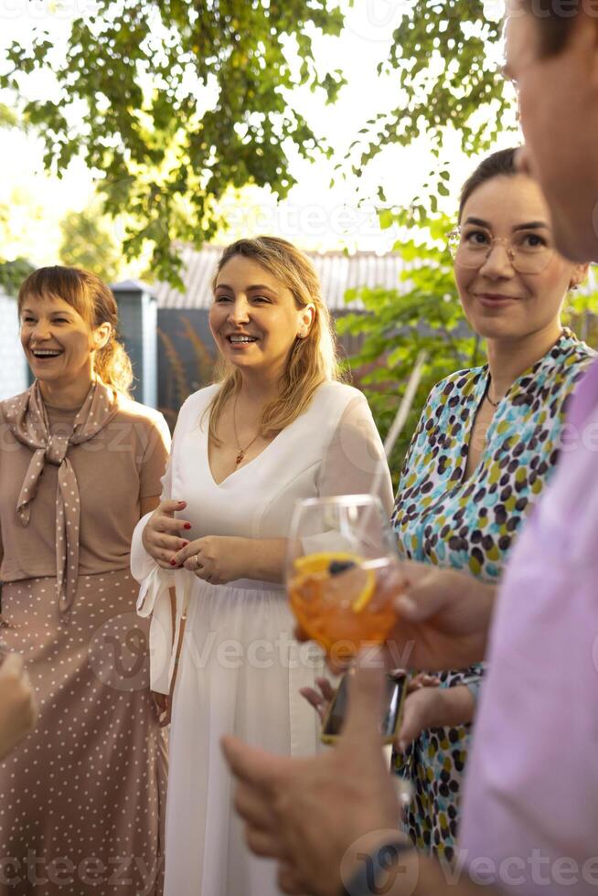 Group of beautiful happy people communicating and smiling while spending time on weding outdoors part photo