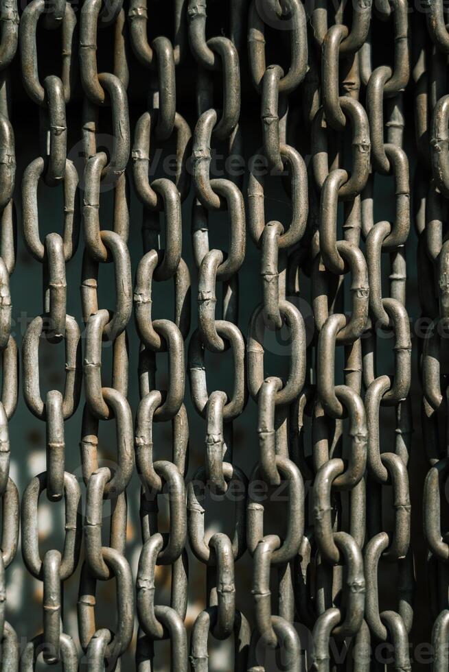 Chains background. Vertically hanging chains on a lawn background photo