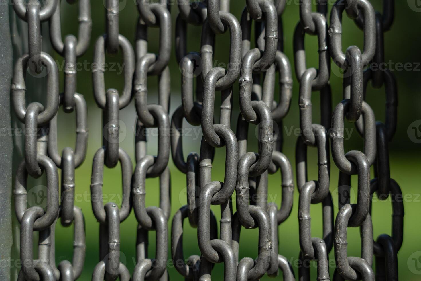 Chains background. Vertically hanging chains on a lawn background photo