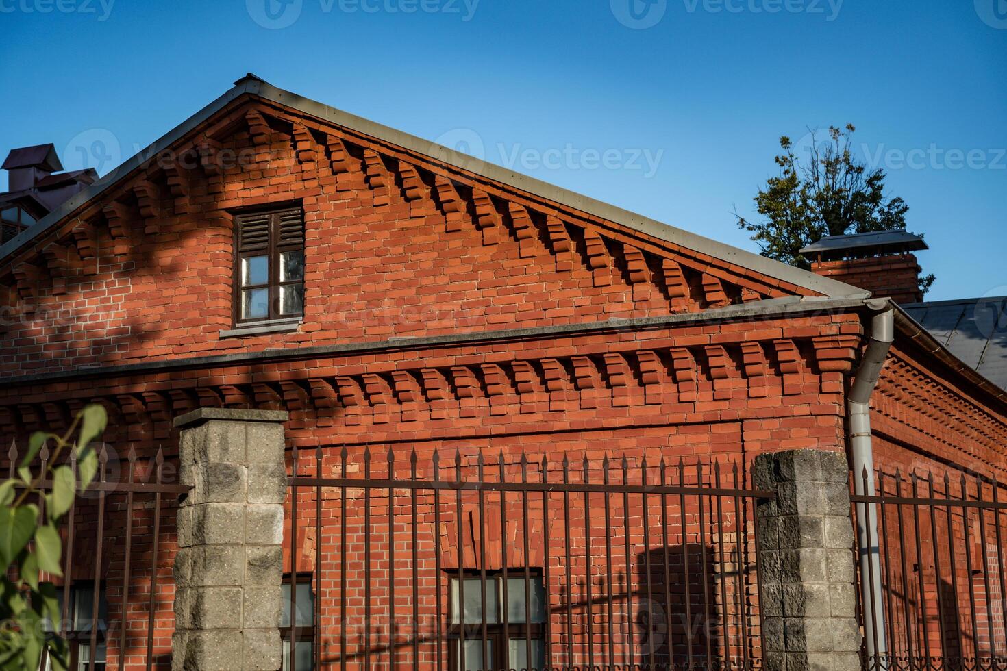 An old, renovated, brick house, behind a fence photo