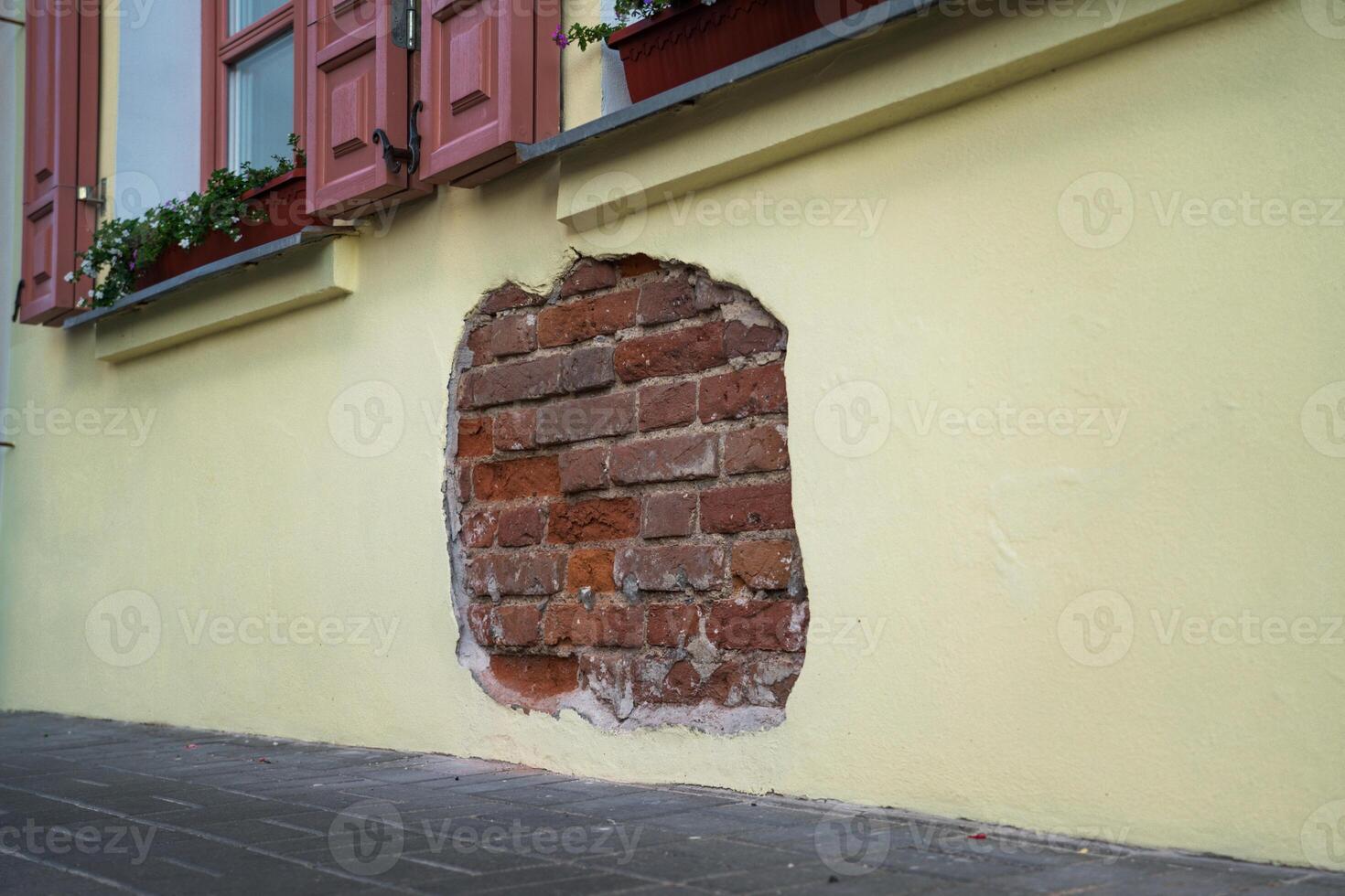 The fallen plaster from the wall of the building from under which the brickwork is visible photo