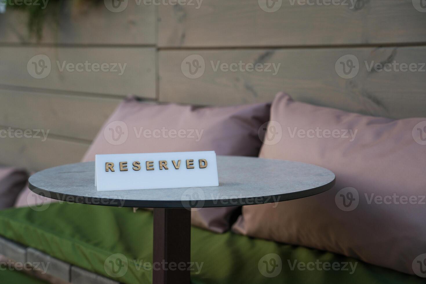 The sign is reserved on the table of the outdoor cafe. Two pink pillows photo