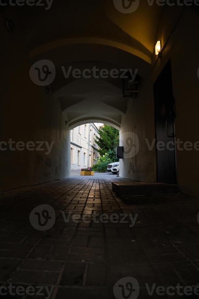 A dark arched passage with a light at the end photo
