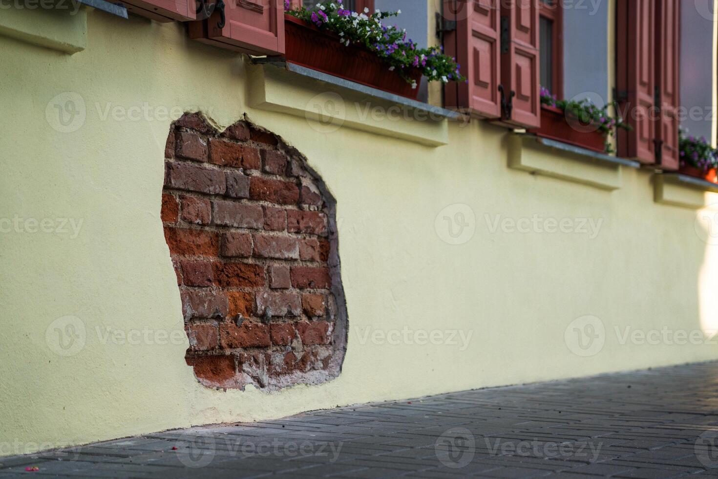 The fallen plaster from the wall of the building from under which the brickwork is visible photo