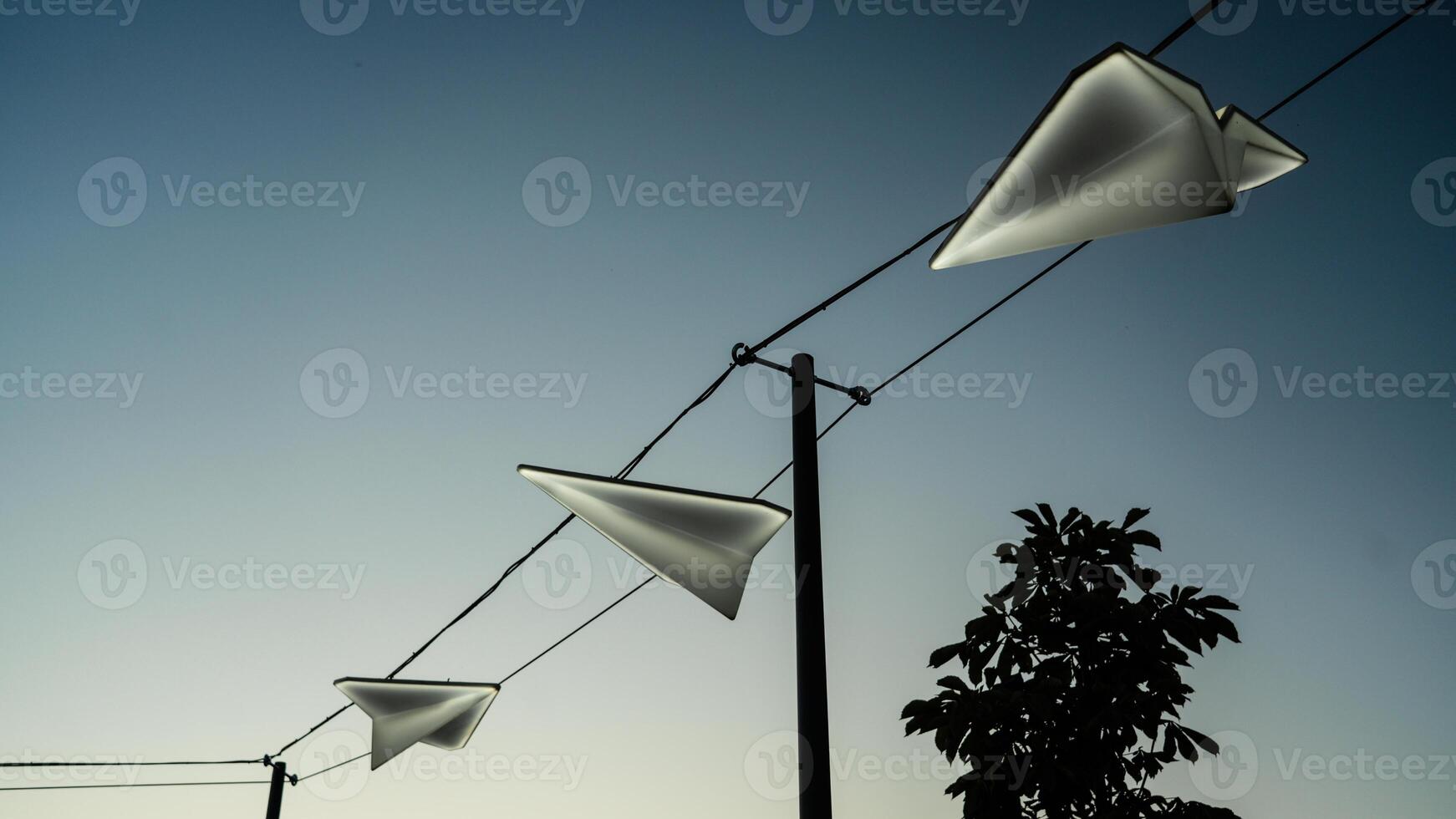 Street lights in the form of paper airplanes, against the background of the sunset sky photo