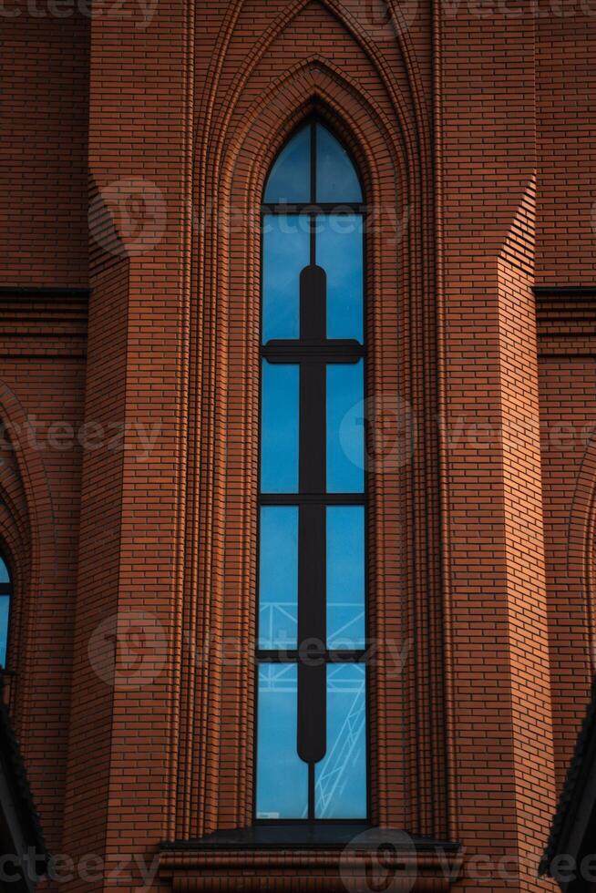 The high, narrow window of the church. The red brick masonry of the church photo