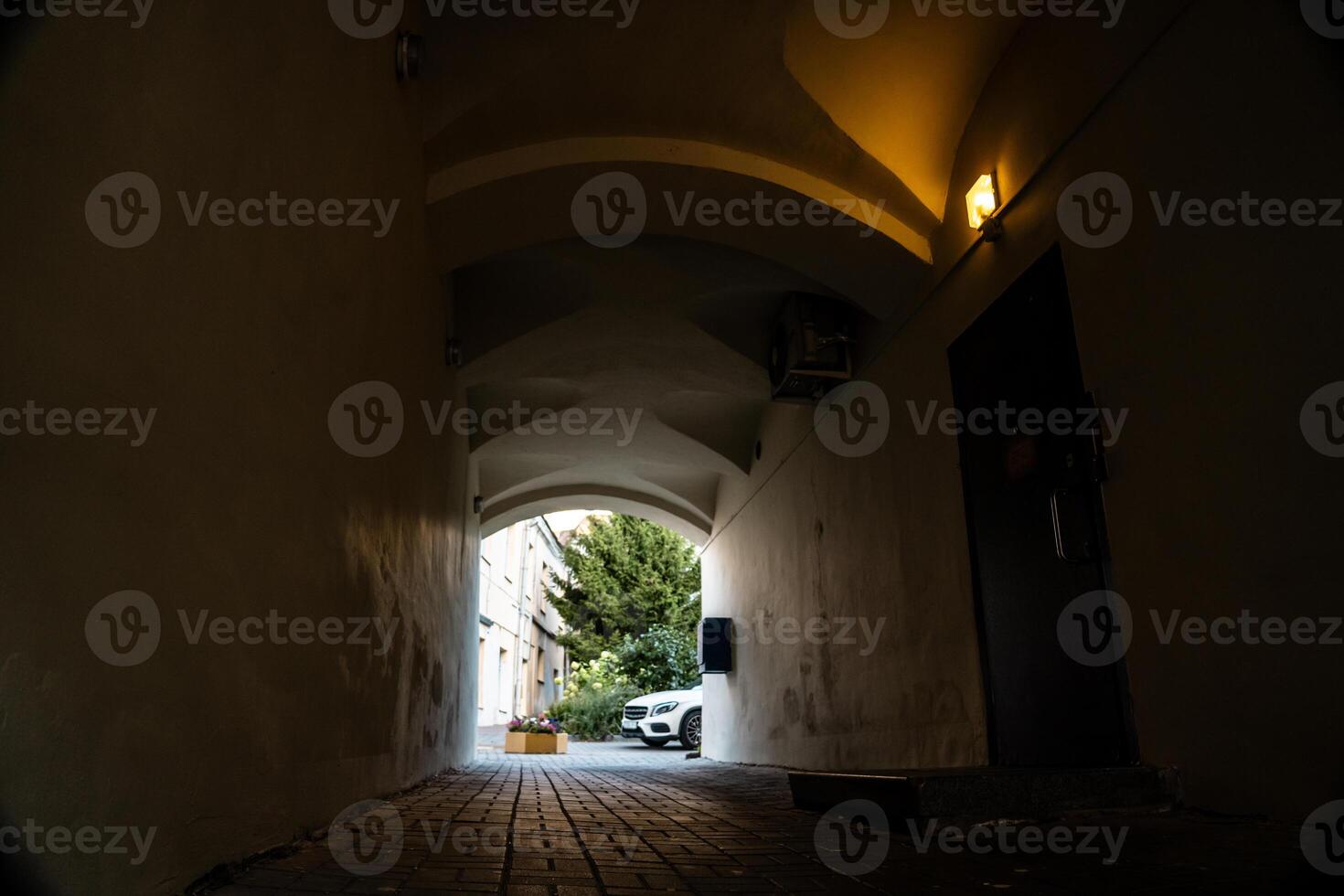 A dark arched passage with a light at the end photo