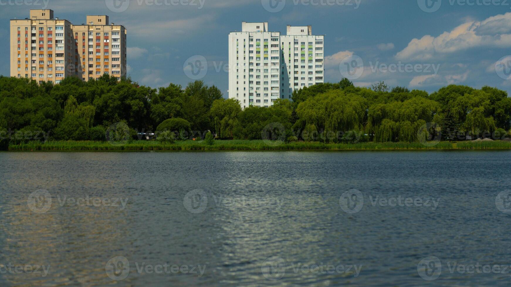 Multi-storey panel buildings, overlooking a large pond and dense trees photo