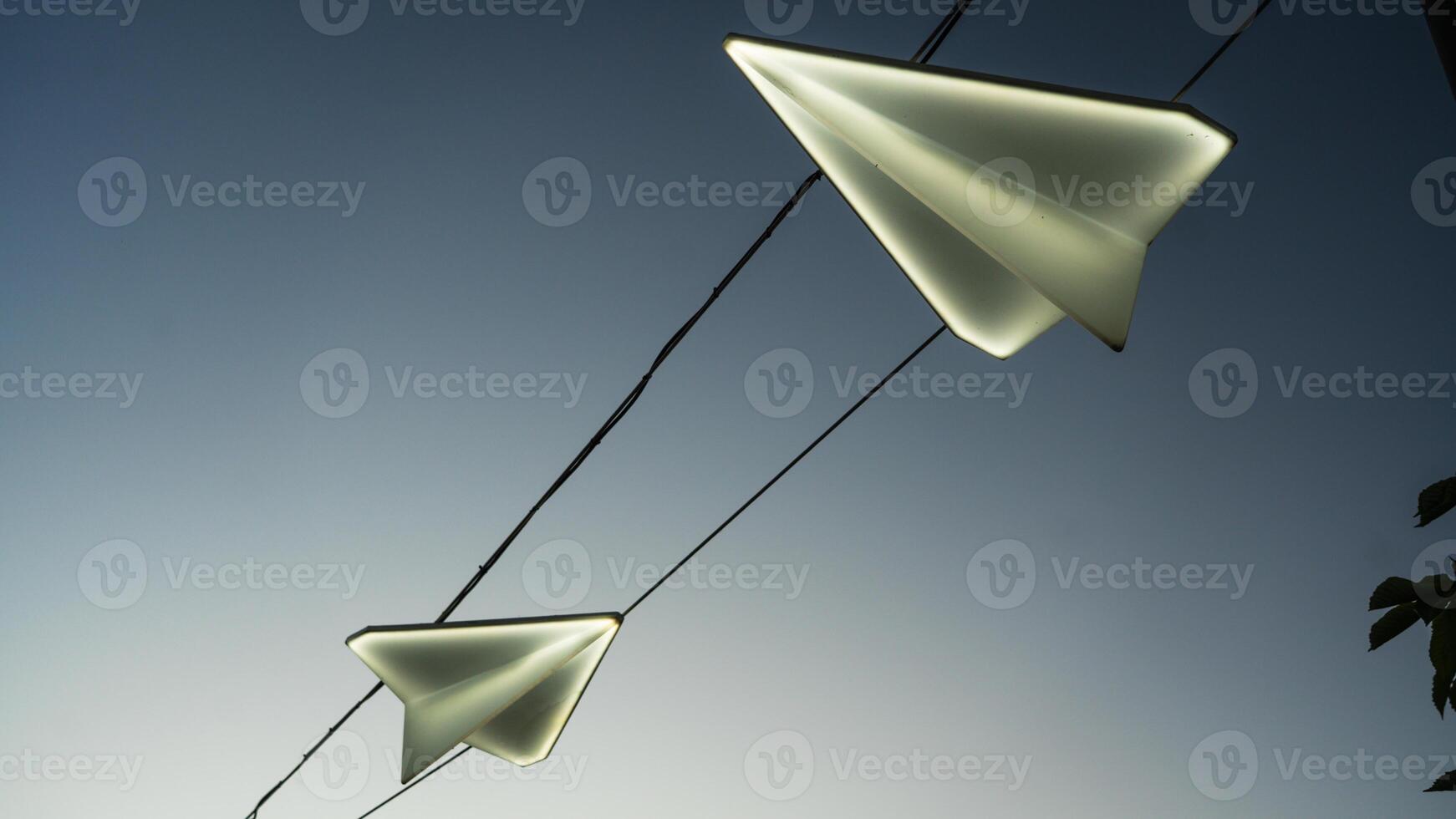 Street lights in the form of paper airplanes, against the background of the sunset sky photo