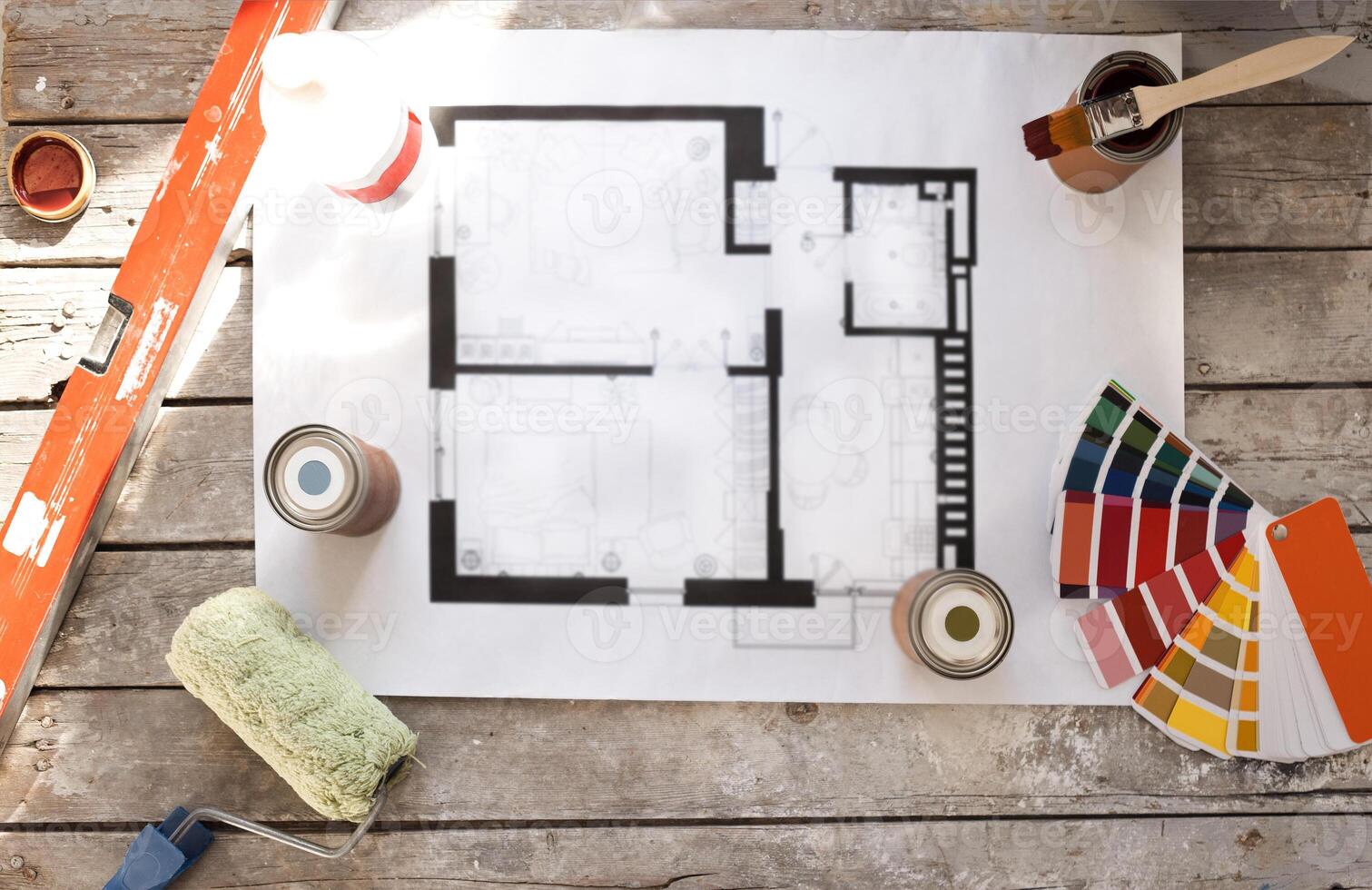 Plan of renovation of house on old wooden table. Top view. Sheet of paper with cans of paint and brushes, palette for choosing colors, construction level and roller. photo
