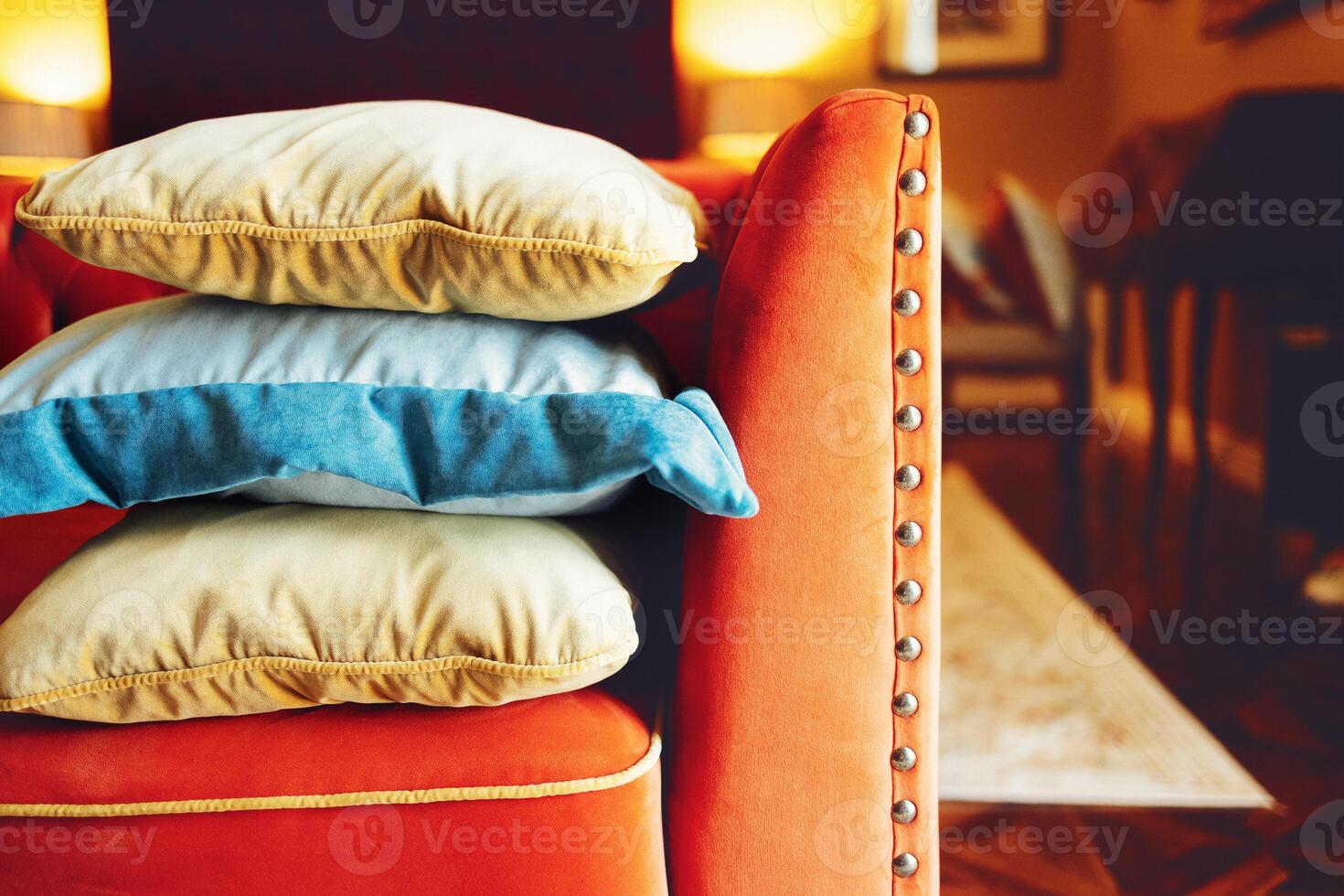 Orange, blue and beige pillows on a red comfortable sofa photo