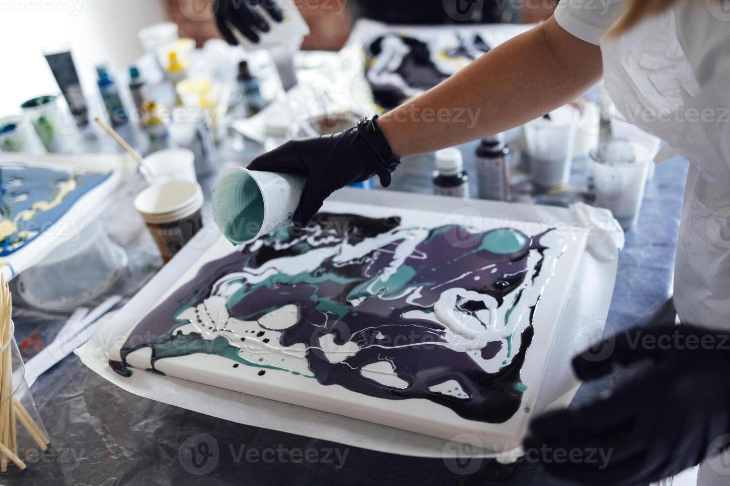 Master class on an Acrylic Fluid Pouring. Young women paint with liquid acrylic in an art workshop photo