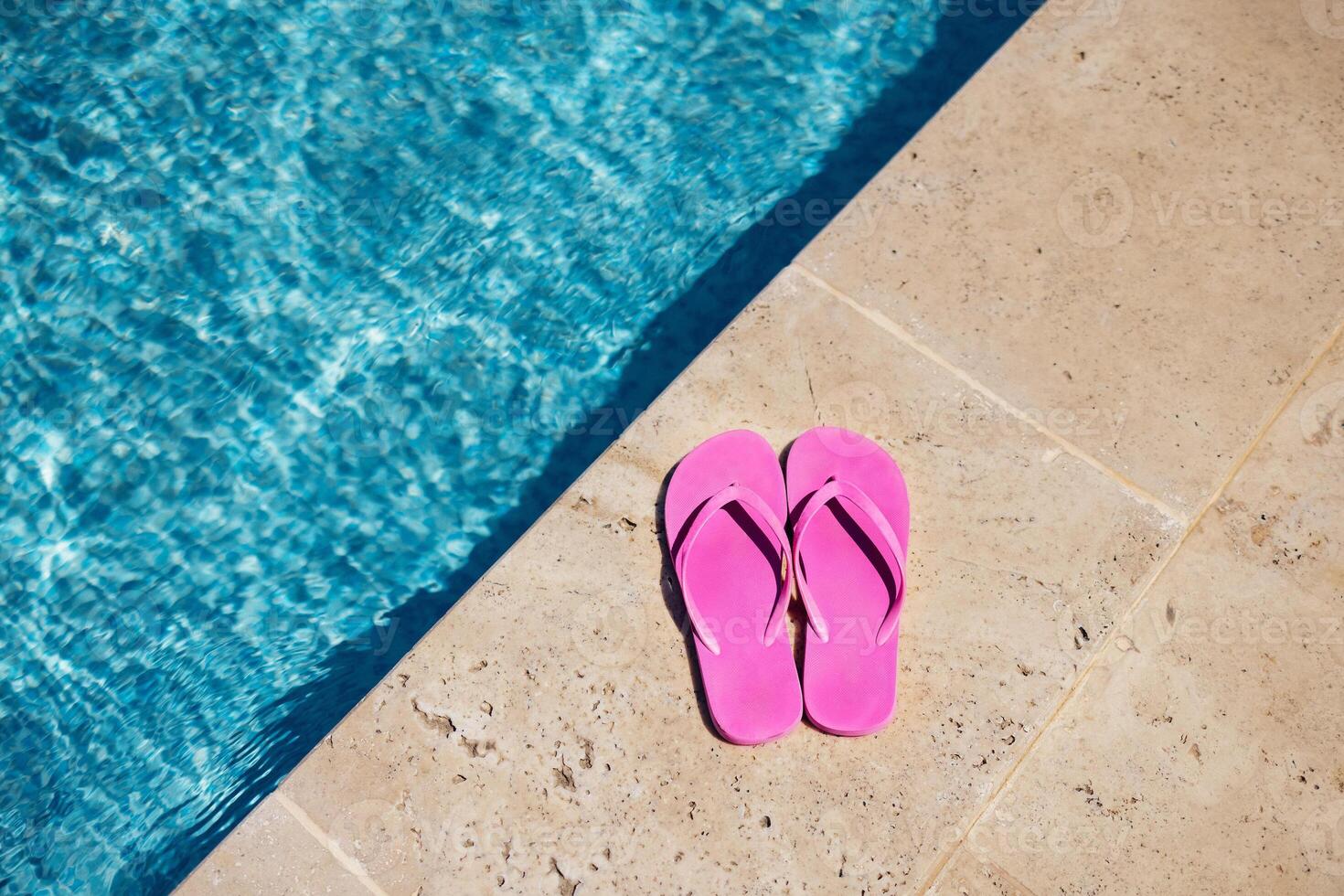 Pink flipflop on the granite poolside while vacation at the hotel. photo
