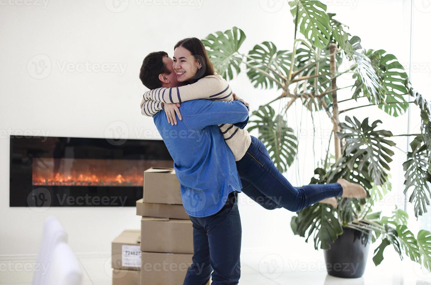 Happy couple with cardboard boxes hugging in new home photo
