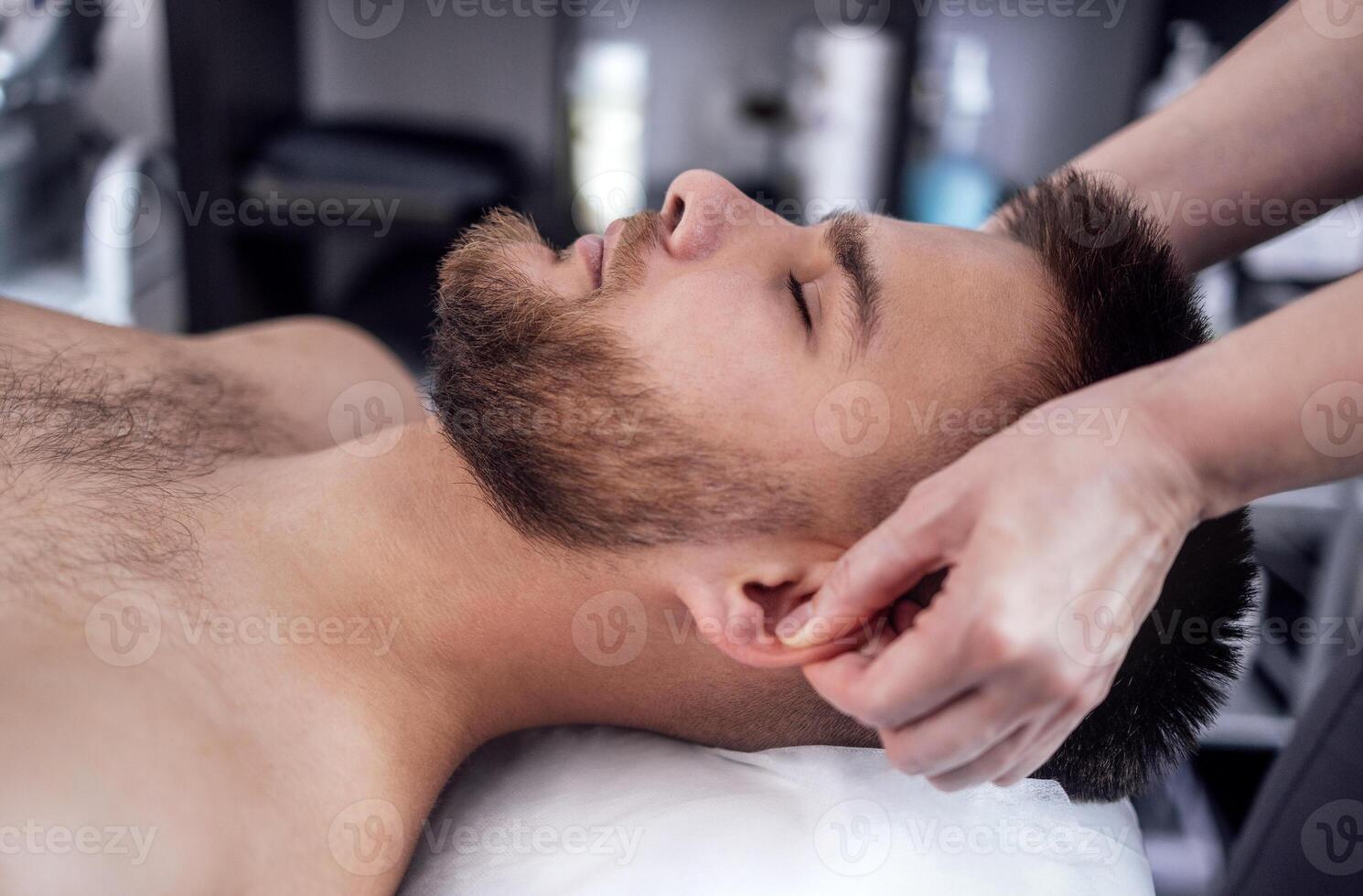 Close up portrait of a young attractive man getting facial massage photo