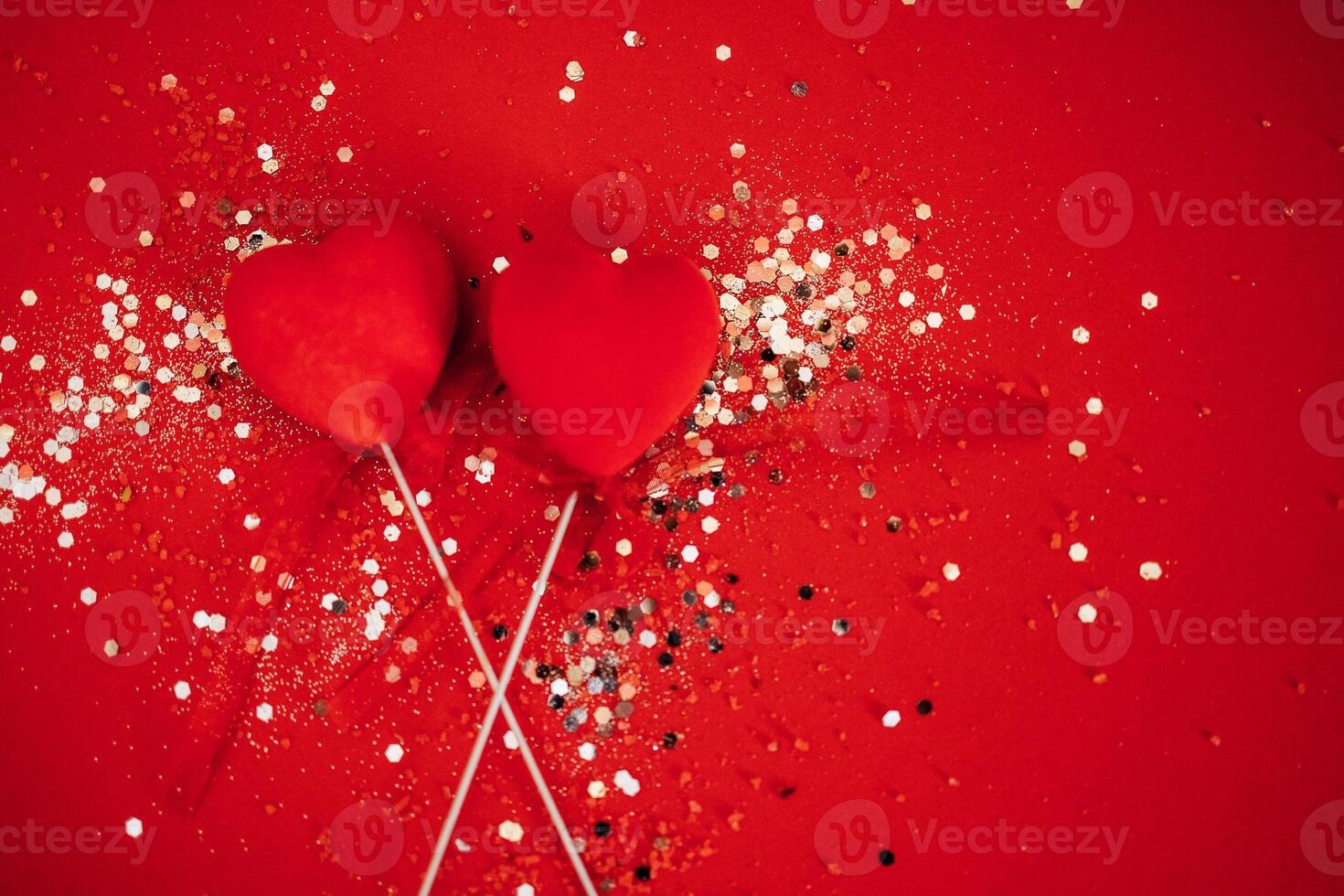 Two decorative hearts on a stick with ribbon. Bright background with silver sequins and round confetti. photo