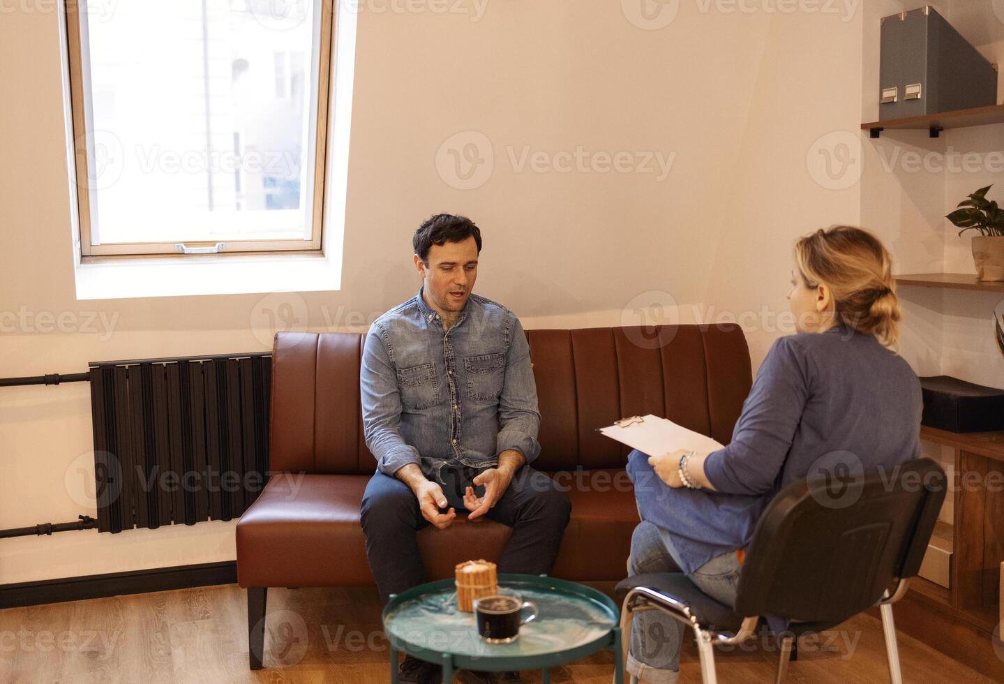 Nice serious pleasant man visiting a psychologist and having a psychological session while dealing with problems in relationships photo