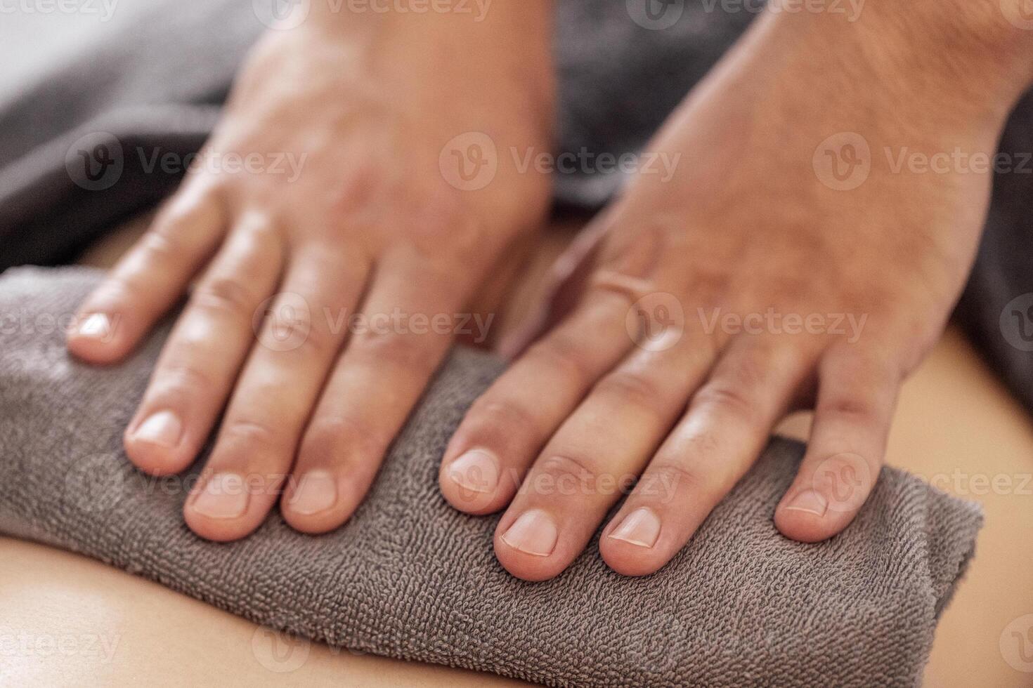 Close-up of neat male masseur hands lying on a towel. A massage therapist does a back massage in a spa salon or clinic. photo