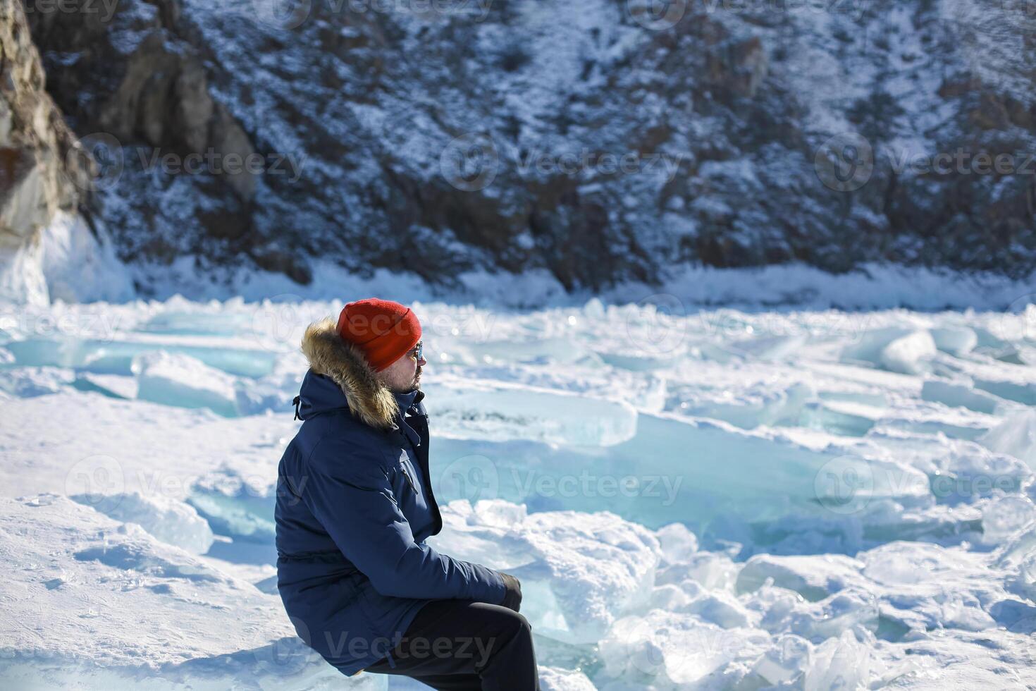 Portrait of the man tourist in red cap and blue jacket wearing sunglasses on ice photo