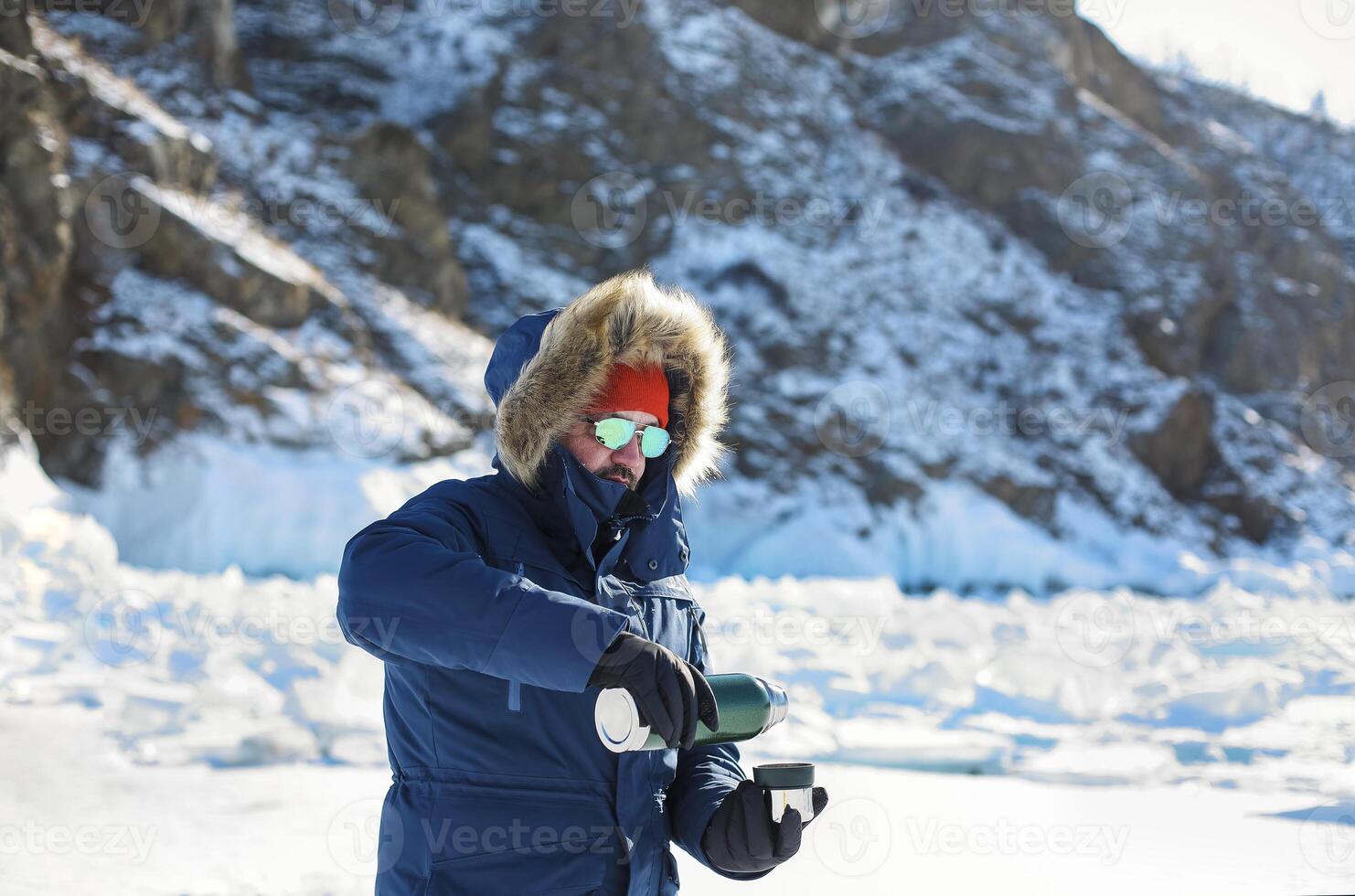 Man in blue jacket pours boiling water from a thermos that turns into a halo a ball over her head photo