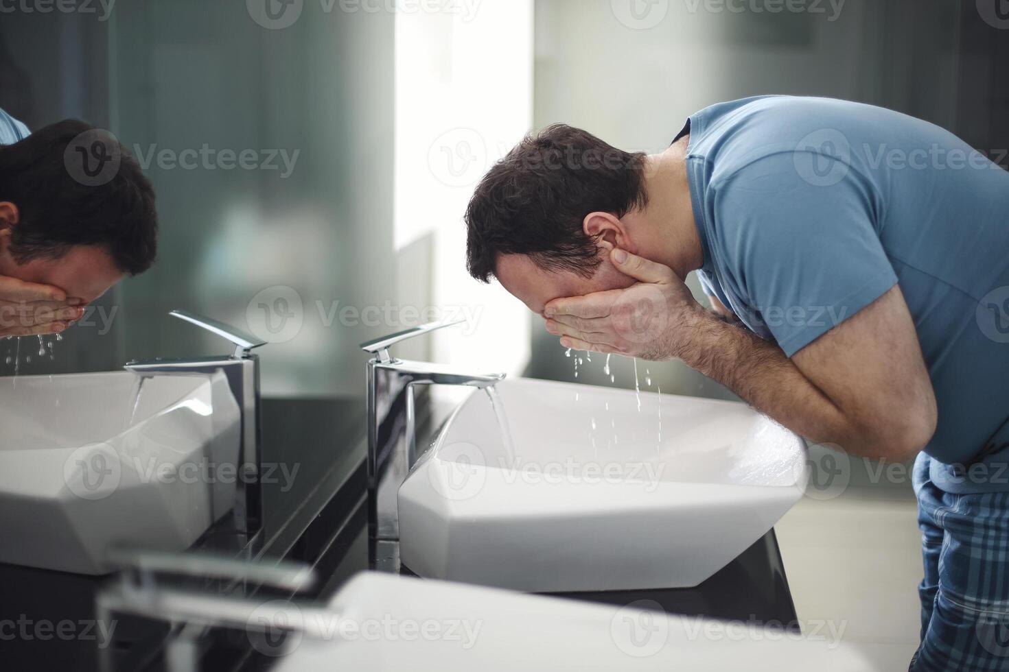 Man washing his face in bathroom photo