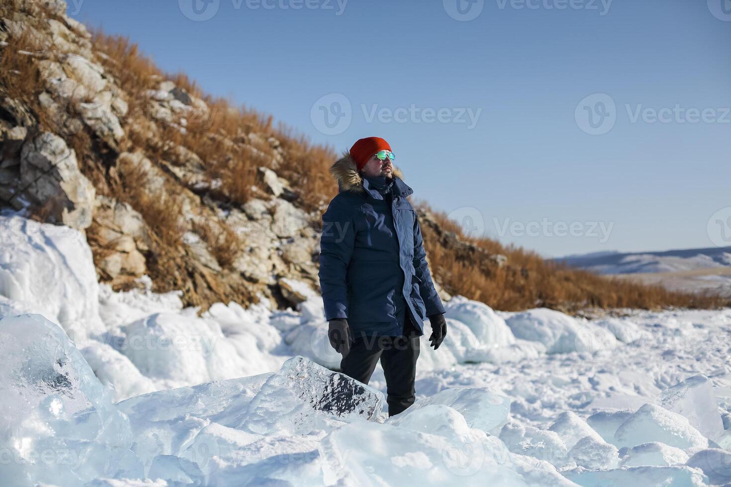 Portrait of the man tourist in red cap and blue jacket wearing sunglasses on ice photo