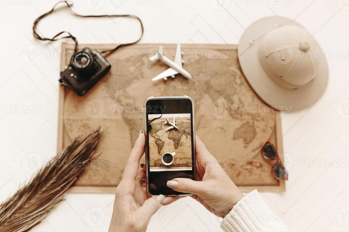 Top view of female hands with smartphone making photo from above of vintage looking world map