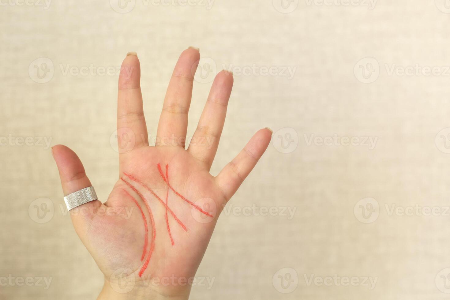 Palmistry. Female palm with life lines drawn with felt-tip pen isolated on light beige background photo