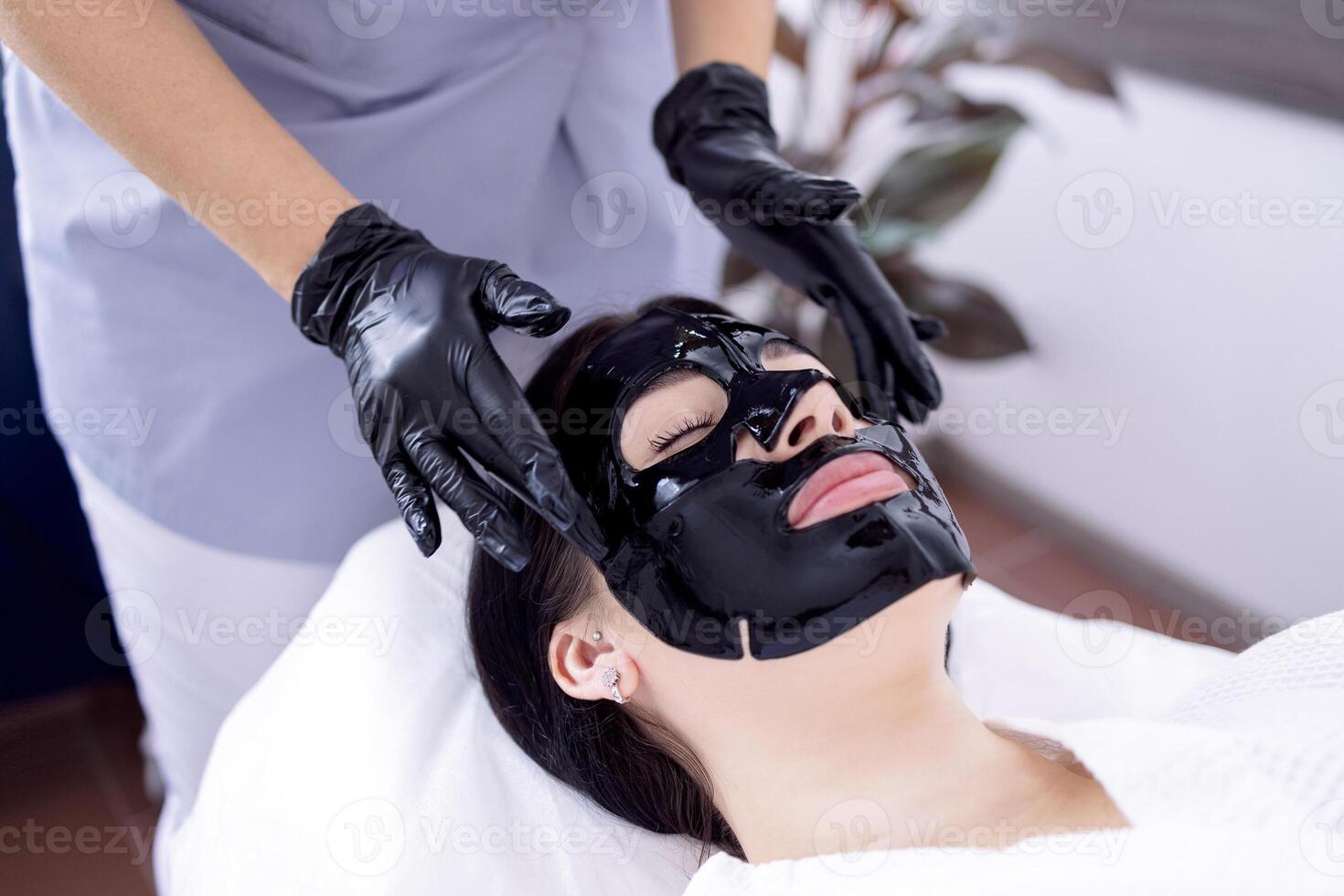 Beautiful caucasian woman with black silicone mask for the skin photo