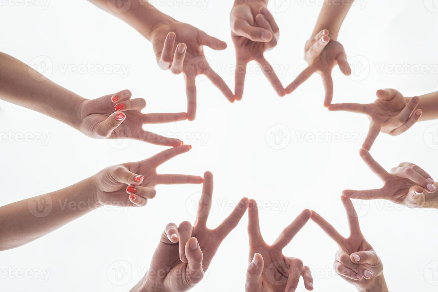 Men and women use their fingers to make a star on a white background. Bottom view. The hands of people with the symbol of peace. photo
