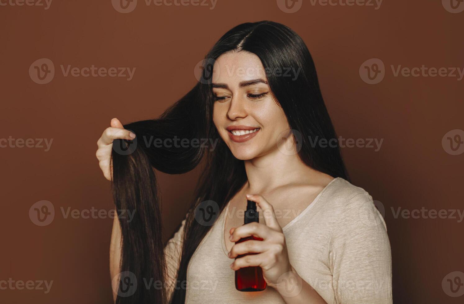 a woman is holding a bottle of hair oil photo