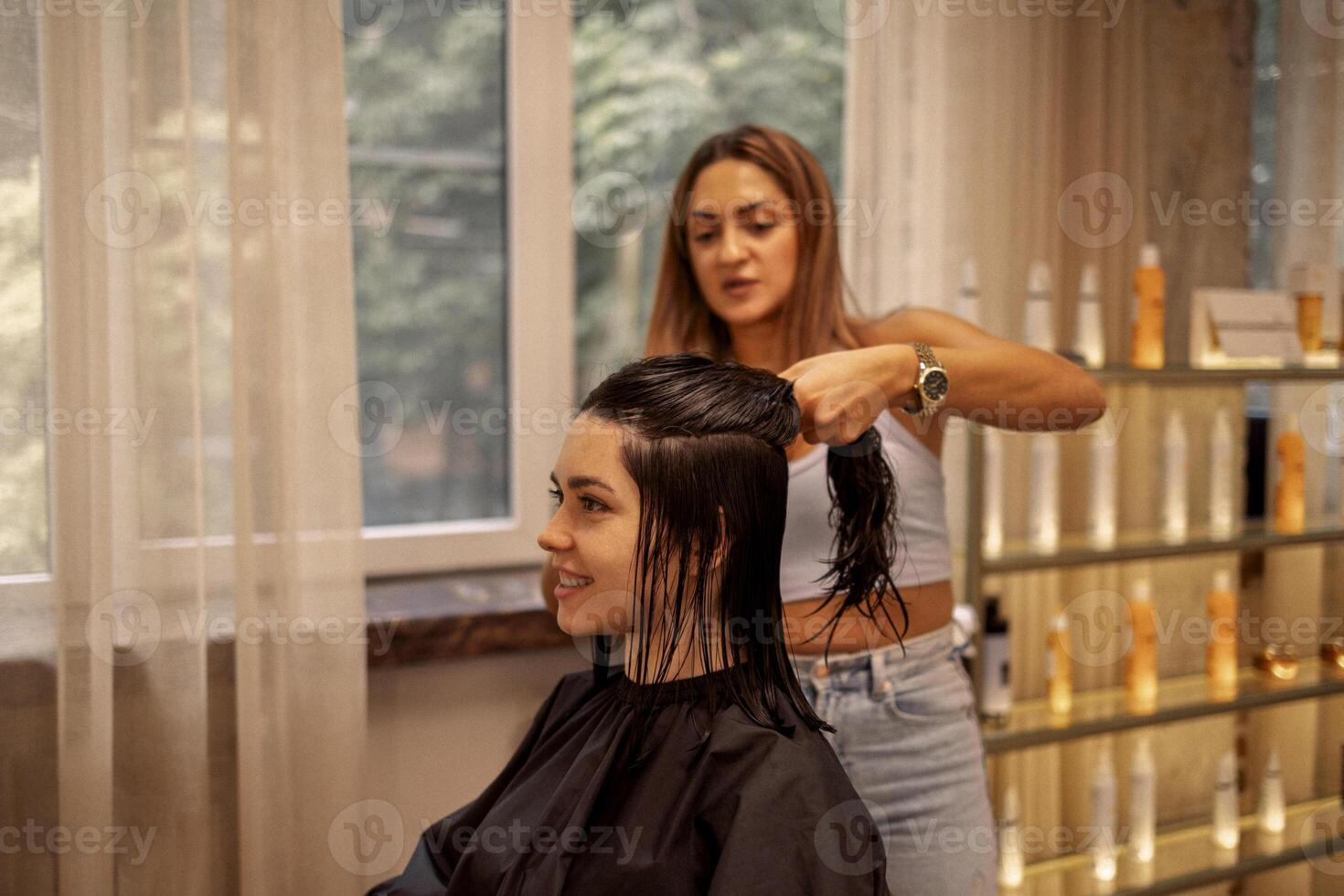 hairdresser cuts hair of woman while working in beauty salon photo
