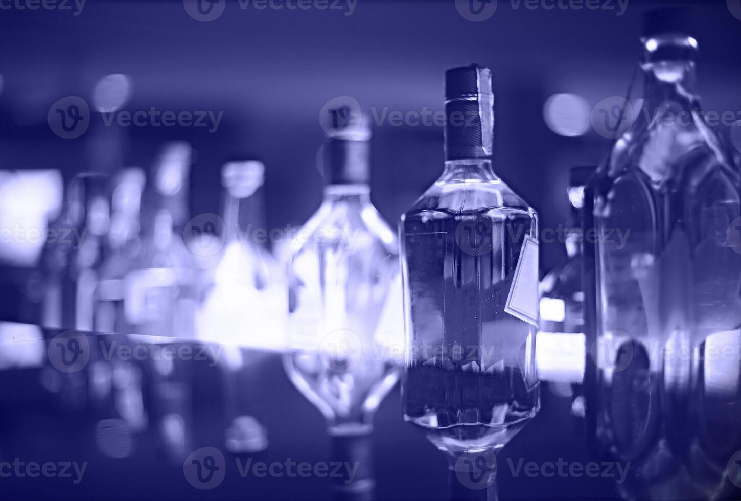 Bar counter with bottles in blurred violet background photo