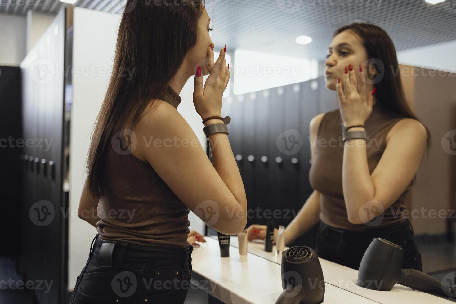 a woman is looking in the mirror while applying makeup photo