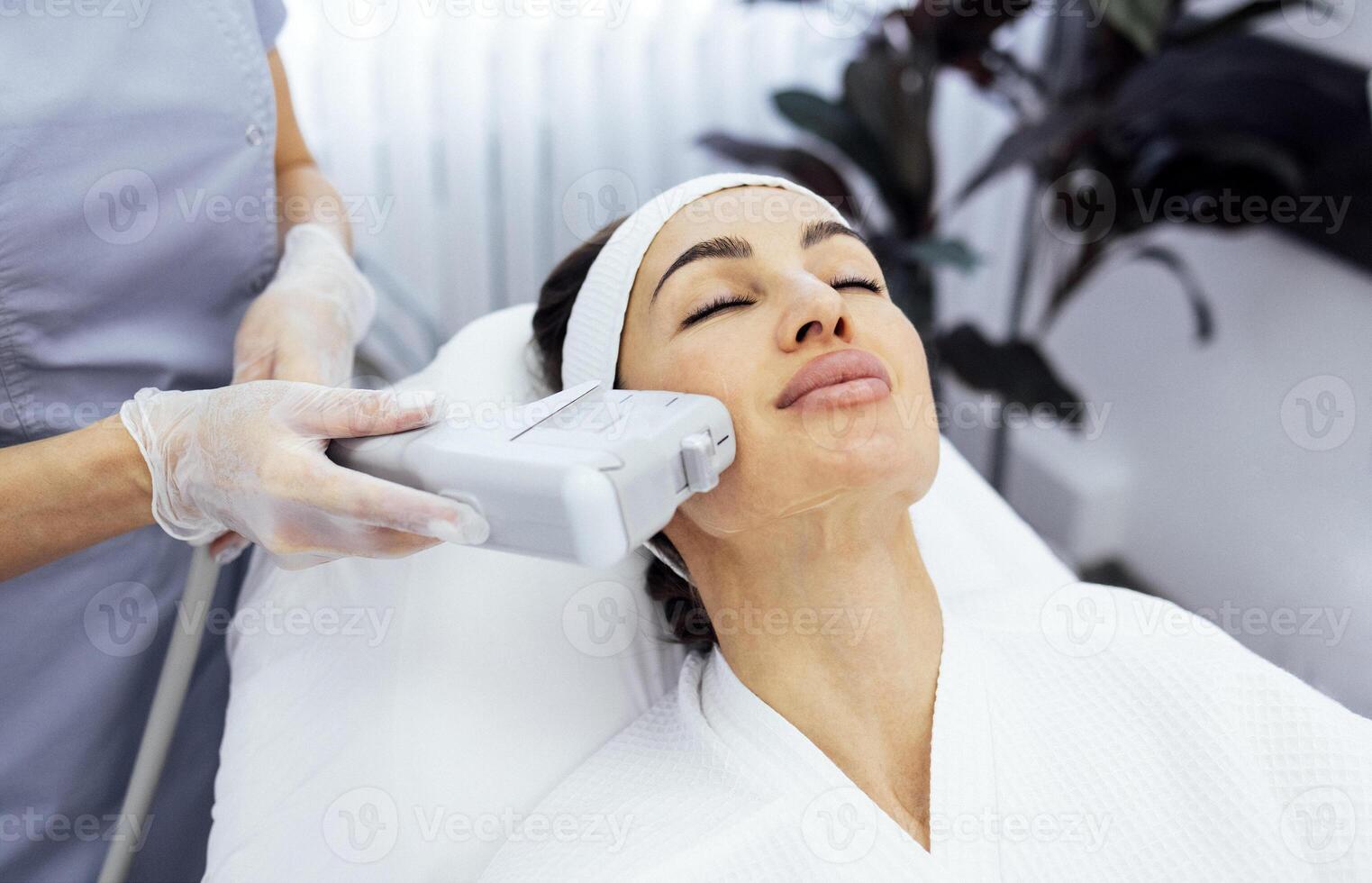 Portrait of relaxed young female client getting SMAS ultrasound face lifting massage photo