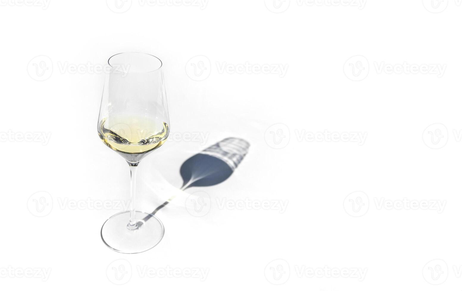 Glasse with white wine, flat lay. Pastel light table in sunlight with long shadow. photo
