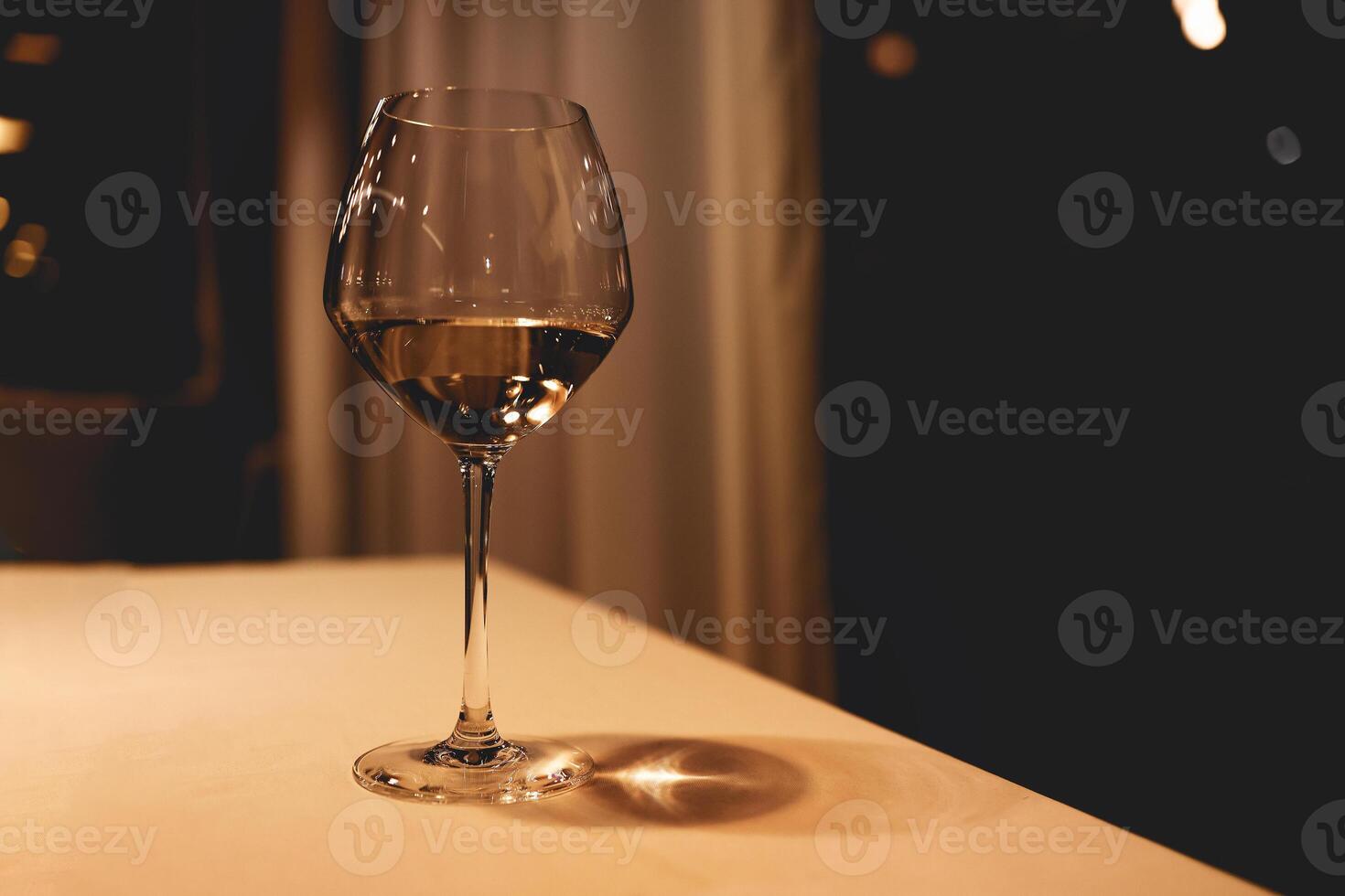 One elegant glass of white wine on high stem on light color table. photo