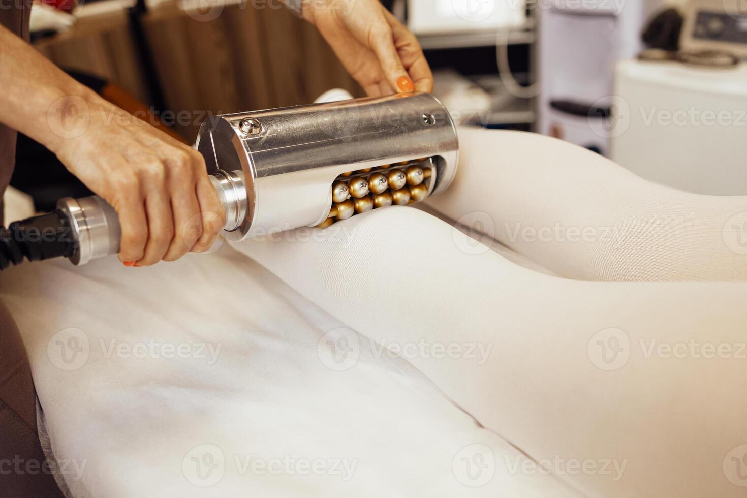 Faceless beautician using massager to remove fat from hips of anonymous customer photo